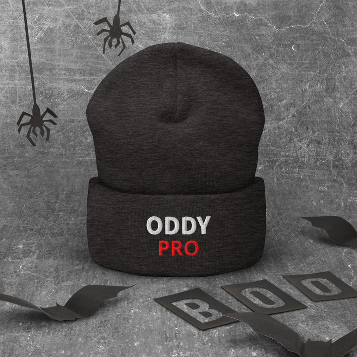 Oddy Pro Cuffed Beanie in black, featuring embroidered text, set against a spooky gray background.