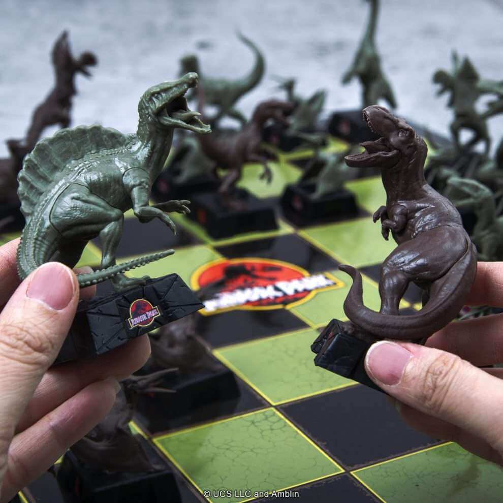 Jurassic Park Chess Set featuring Spinosaurus and T-Rex pieces on a themed chess board.
