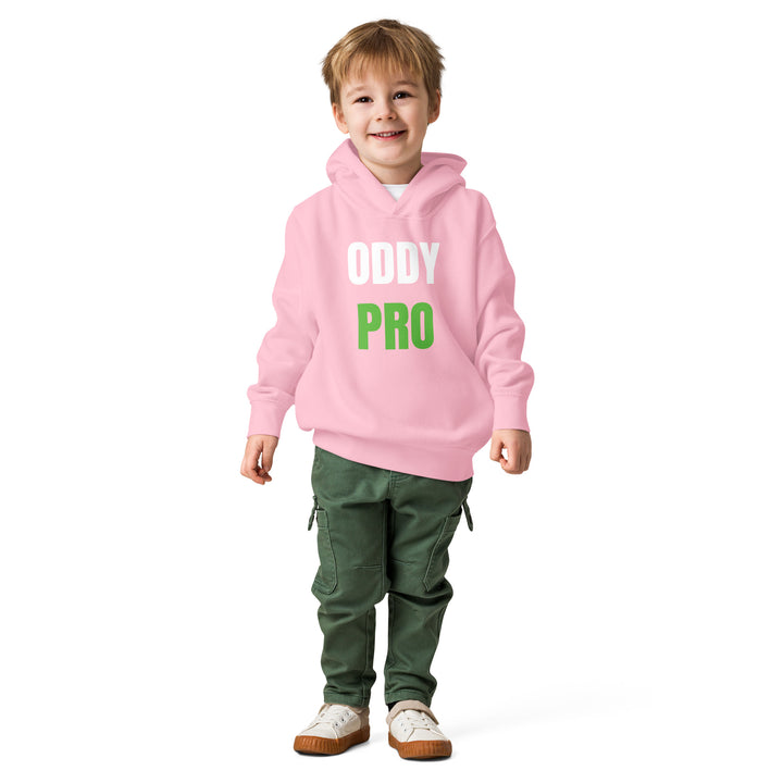 A toddler wearing an Oddy Pro Toddler fleece pullover hoodie in pink, styled with green pants and a cheerful expression.